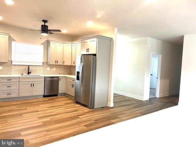 kitchen featuring appliances with stainless steel finishes, a sink, ceiling fan, baseboards, and recessed lighting