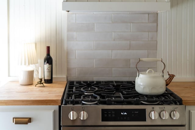 interior details featuring butcher block countertops, decorative backsplash, and stainless steel range with gas cooktop
