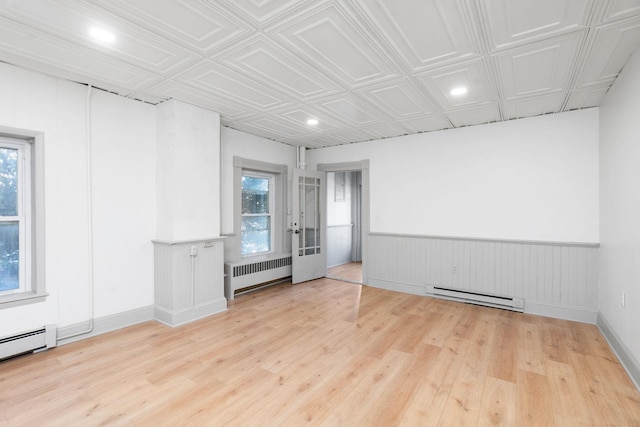 spare room with an ornate ceiling, wood finished floors, radiator heating unit, a baseboard radiator, and wainscoting