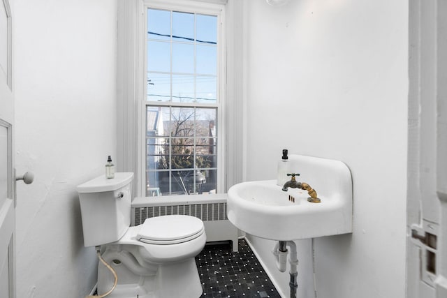 half bath featuring toilet, radiator, a sink, and a wealth of natural light