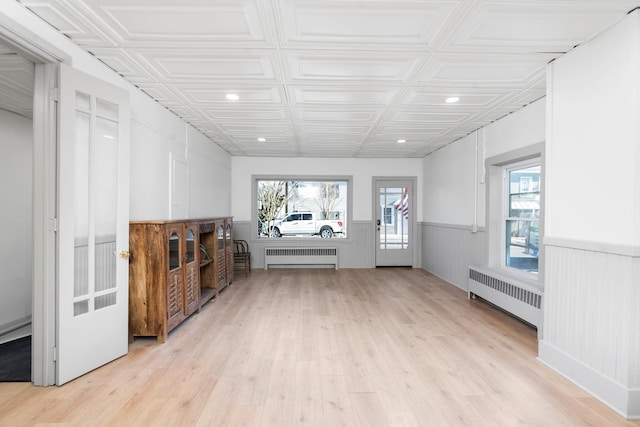 unfurnished living room featuring wood finished floors, a healthy amount of sunlight, and radiator heating unit