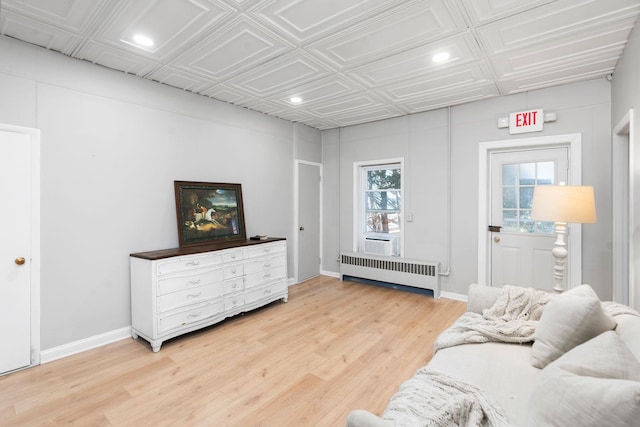 living area featuring light wood finished floors, radiator, an ornate ceiling, baseboards, and recessed lighting