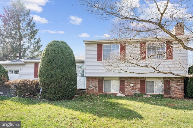  - split level home featuring a front lawn, a chimney, and brick siding