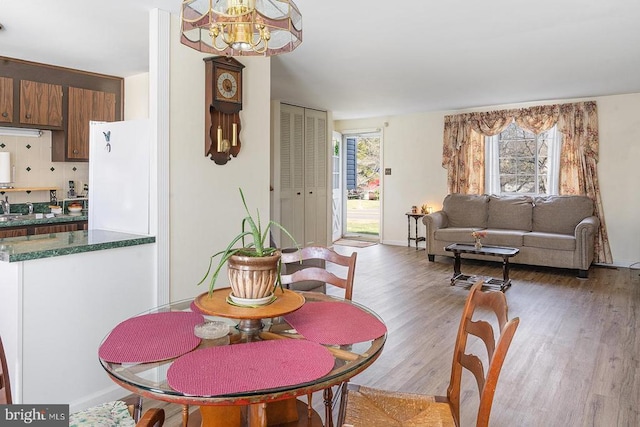  - dining space with light wood-type flooring, a chandelier, and baseboards