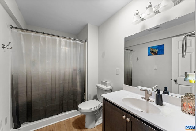 bathroom with toilet, a shower with curtain, wood finished floors, vanity, and visible vents