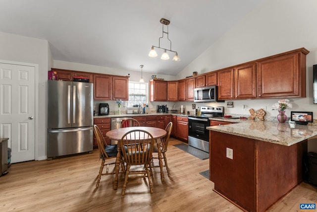 kitchen featuring decorative light fixtures, a peninsula, stainless steel appliances, and light wood-style floors