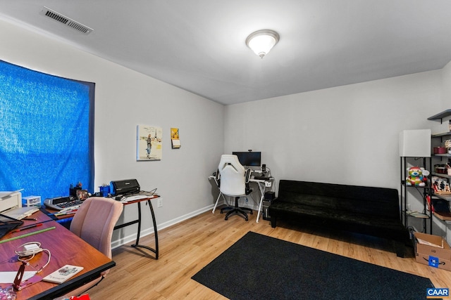 office space with baseboards, visible vents, and wood finished floors
