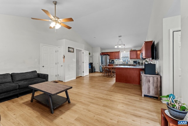 living area with light wood-type flooring, a ceiling fan, and high vaulted ceiling