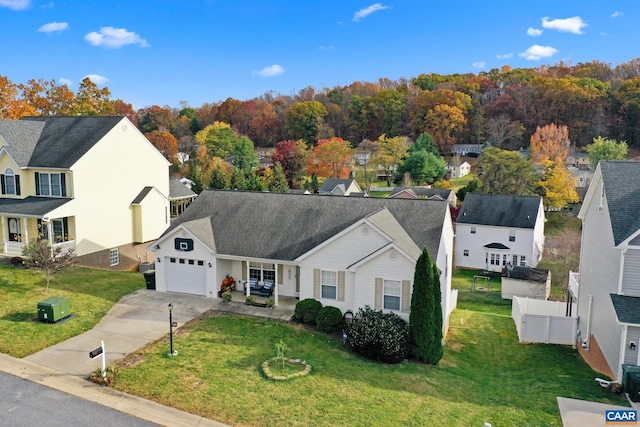 view of front facade featuring fence, an attached garage, a residential view, driveway, and a front lawn