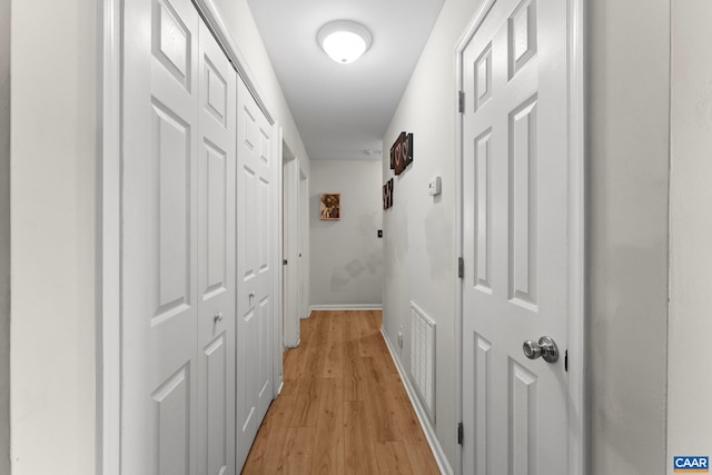 corridor featuring baseboards, visible vents, and light wood-style floors