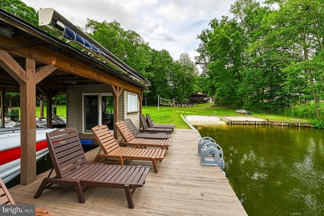 dock area with a water view, a lawn, and view of wooded area