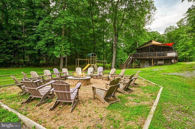 view of grassy yard with an outdoor fire pit, stairway, a wooden deck, and a sunroom