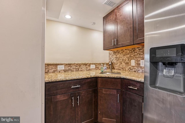 kitchen with stainless steel refrigerator with ice dispenser, a sink, decorative backsplash, dark brown cabinets, and recessed lighting