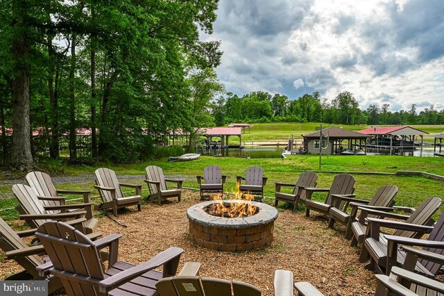 view of home's community with a fire pit, a yard, a water view, and view of scattered trees