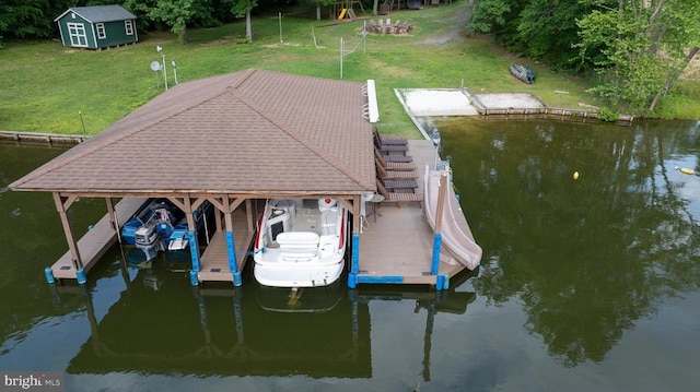 dock featuring boat lift, a lawn, and a water view