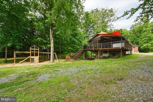 view of grassy yard featuring stairway, a wooden deck, and a playground