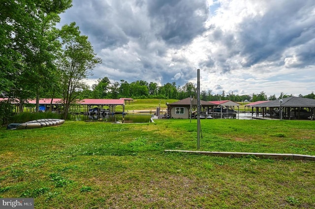 view of community with boat lift, a dock, a lawn, and a water view