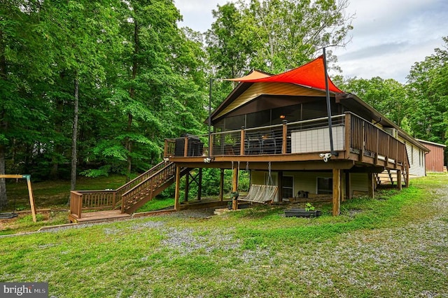 back of property featuring stairway, a deck, and a lawn