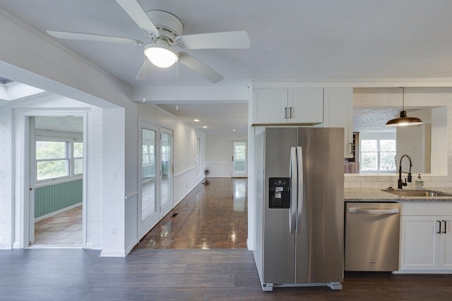 kitchen featuring a sink, stainless steel appliances, plenty of natural light, and light stone countertops