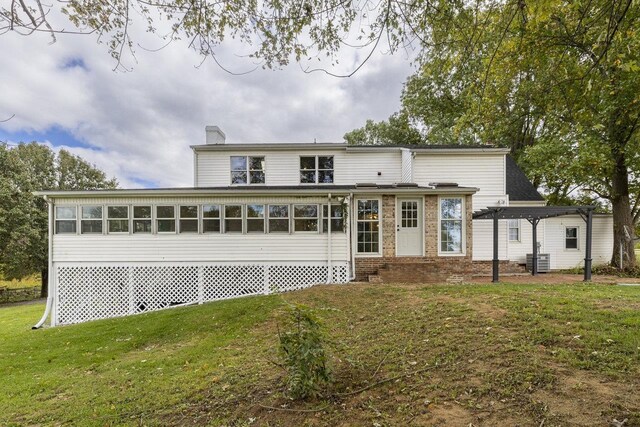 back of property featuring a yard, entry steps, a chimney, central AC unit, and a sunroom
