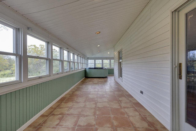 unfurnished sunroom with a wealth of natural light, wooden walls, and vaulted ceiling