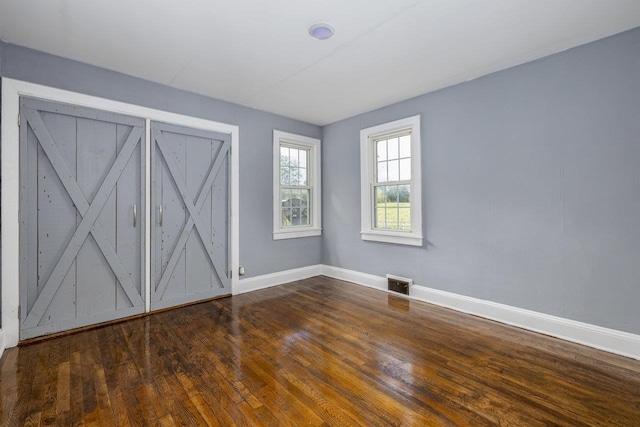 unfurnished bedroom featuring wood finished floors, visible vents, and baseboards