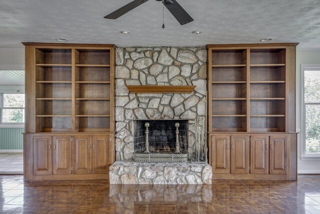 unfurnished living room with ornamental molding, a textured ceiling, a fireplace, a ceiling fan, and baseboards