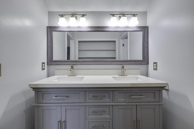 full bathroom featuring double vanity, a textured ceiling, and a sink