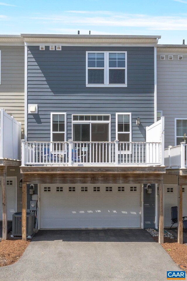 rear view of house with a garage, driveway, and central AC