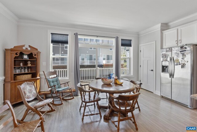 dining space with light wood finished floors and crown molding