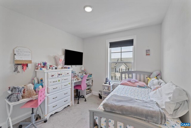 carpeted bedroom featuring an office area and baseboards