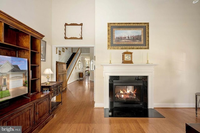10207 Iverson Ave, Fredericksburg, VA 22407 - living area featuring a fireplace with flush hearth, wood finished floors, stairs, baseboards, and a high ceiling