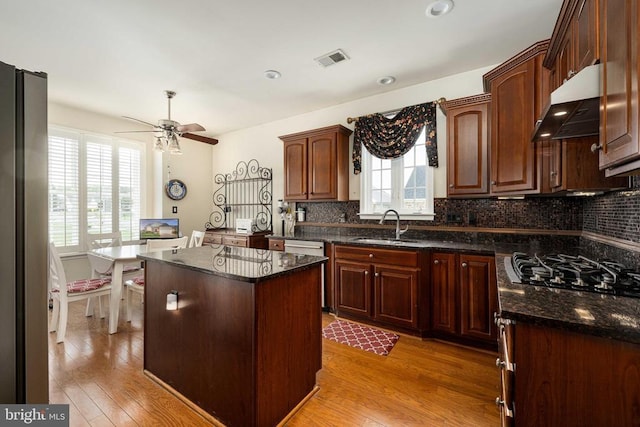 10207 Iverson Ave, Fredericksburg, VA 22407 - kitchen with under cabinet range hood, a sink, a center island, backsplash, and light wood-style flooring