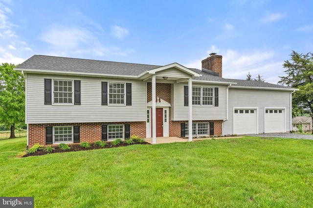 split foyer home with a garage, asphalt driveway, a front lawn, and a chimney