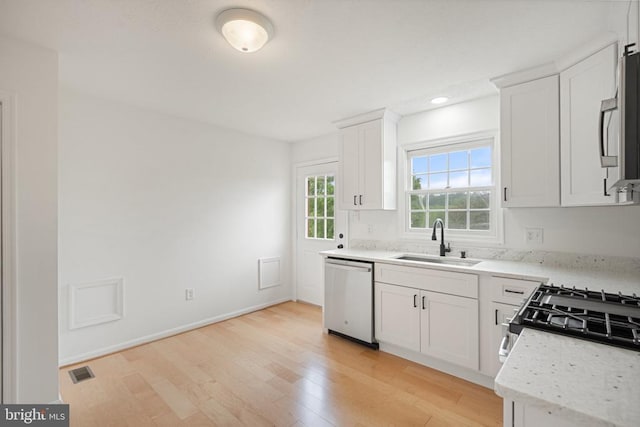 kitchen with appliances with stainless steel finishes, a sink, light wood-style floors, white cabinetry, and recessed lighting