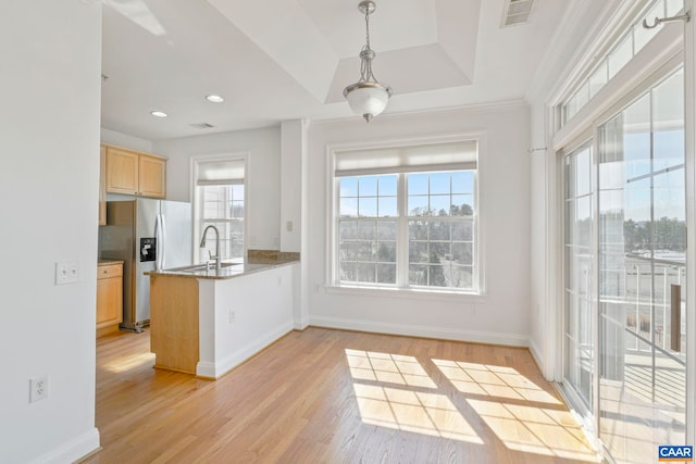 kitchen with a peninsula, light brown cabinets, visible vents, and light wood-style floors