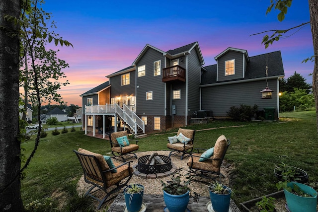 4220 Traveler Rd, Rockingham, VA 22801 - back of house at dusk featuring a balcony, an outdoor fire pit, stairs, a lawn, and a patio
