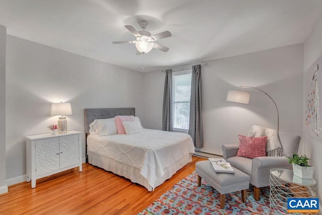bedroom with a baseboard radiator, light wood-style flooring, baseboards, and a ceiling fan