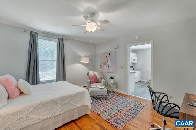 bedroom with connected bathroom, a ceiling fan, wood finished floors, and baseboards