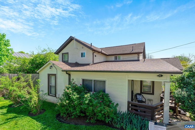 view of front of property featuring a front lawn, stucco siding, roof with shingles, and fence
