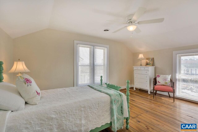 bedroom with multiple windows, visible vents, hardwood / wood-style flooring, and vaulted ceiling
