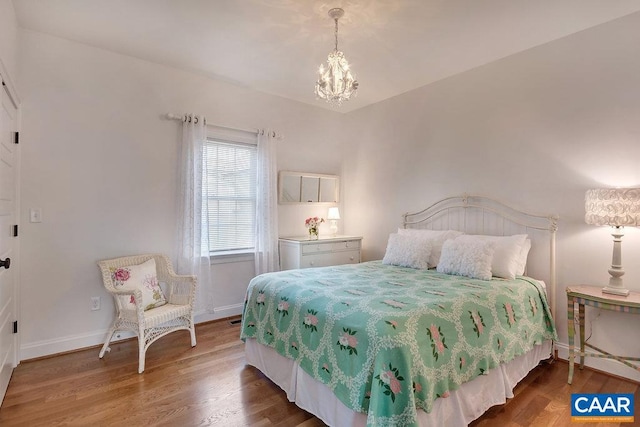 bedroom featuring a chandelier, baseboards, and wood finished floors