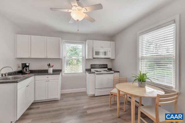 kitchen with a sink, light wood-style flooring, white appliances, and white cabinets