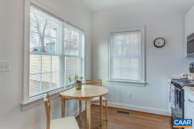 dining area with light wood-style flooring, baseboards, and visible vents