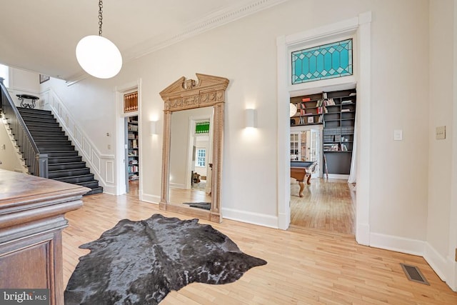  - entryway with wood finished floors, stairway, crown molding, and billiards table
