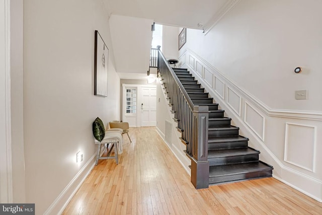  - stairway featuring hardwood / wood-style flooring and crown molding