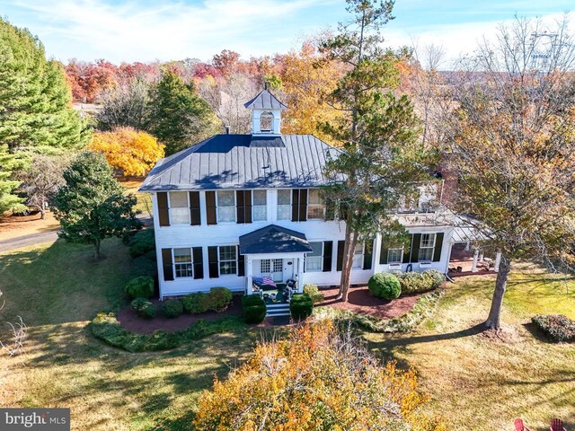  - colonial-style house with a front yard and a standing seam roof
