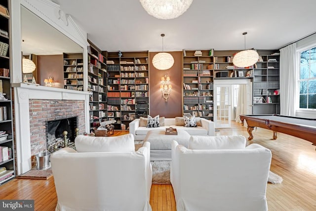  - living room featuring wood finished floors, a fireplace, built in features, and billiards