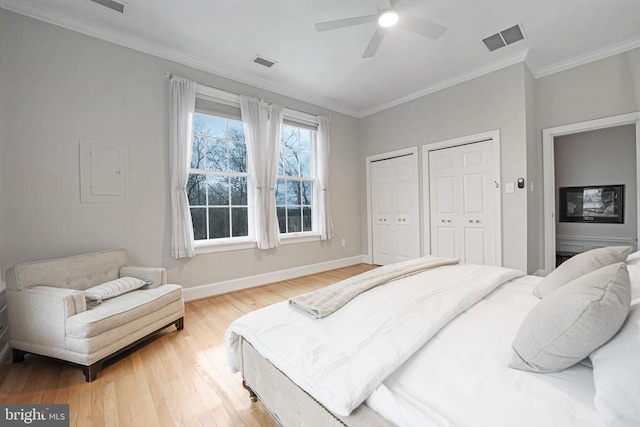  - bedroom featuring multiple closets, light wood-style floors, crown molding, and a ceiling fan