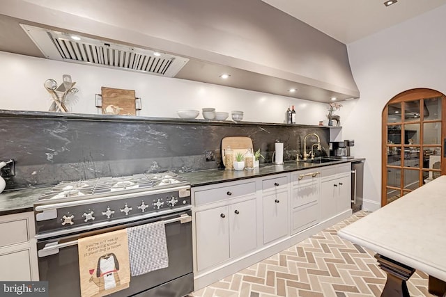 - kitchen with gas range, open shelves, brick patterned flooring, white cabinets, and dark countertops
